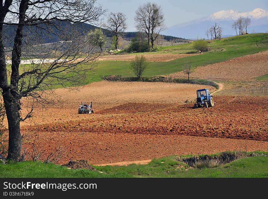 Two tractors plowing the field area