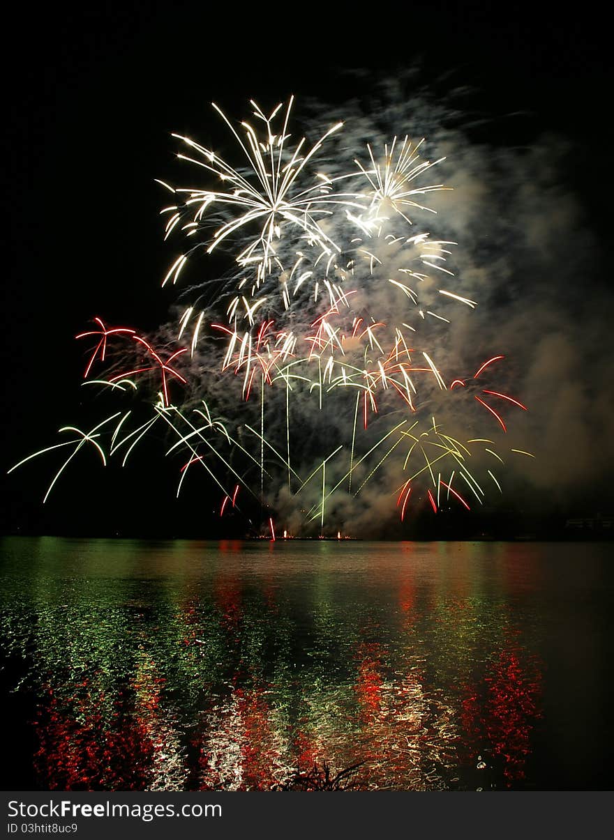 Colorful fireworks on the black sky background and water reflections