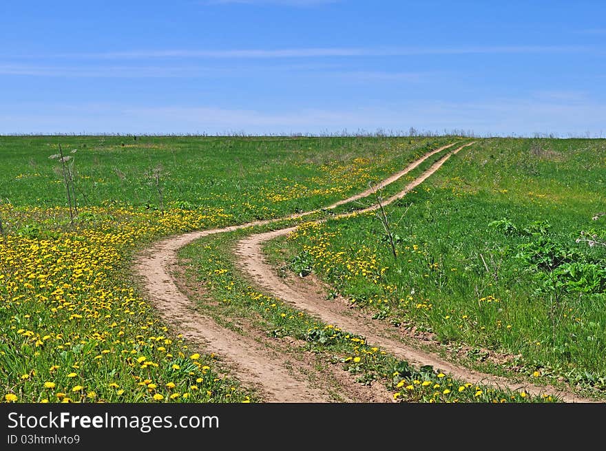 Country dirt road across the field, spring sunny day. Country dirt road across the field, spring sunny day