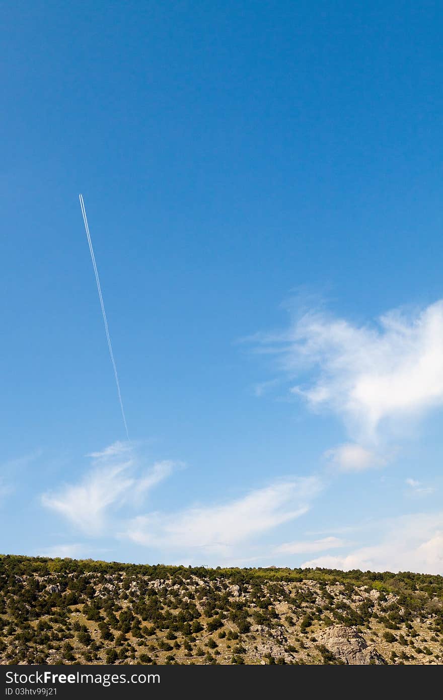 Mountain meadow and an airplane in the sky