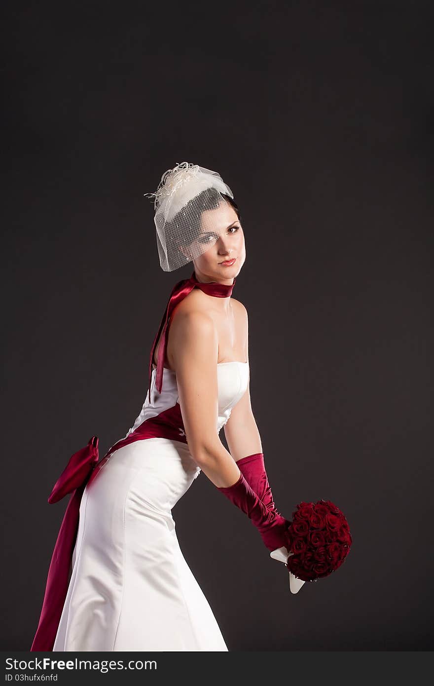 Beautiful bride in wedding dress with bouquet in studio