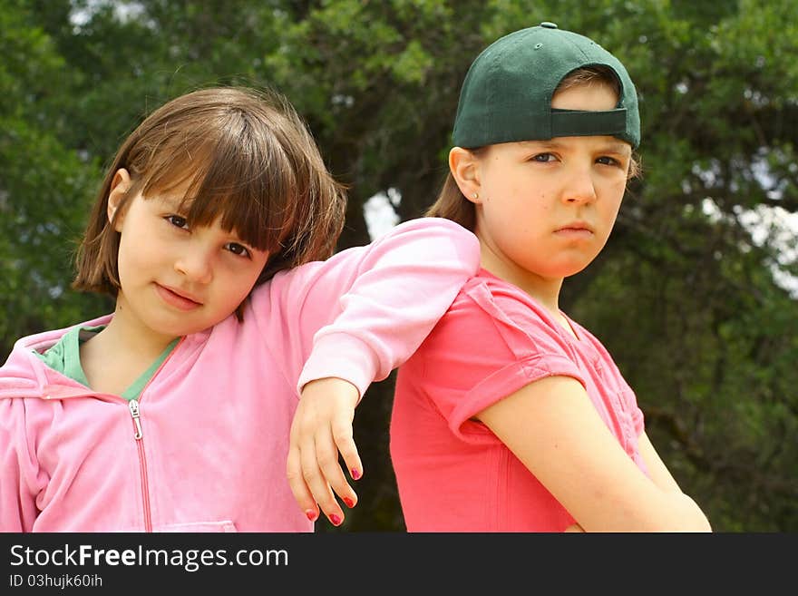 Two cute sisters together with green trees in the background. Two cute sisters together with green trees in the background