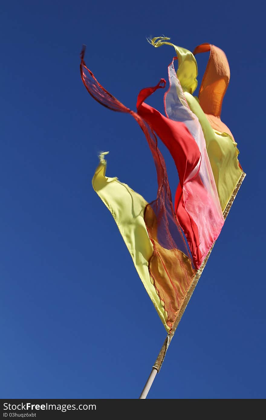 Colourful buddhistic flag against a blue sky. Colourful buddhistic flag against a blue sky