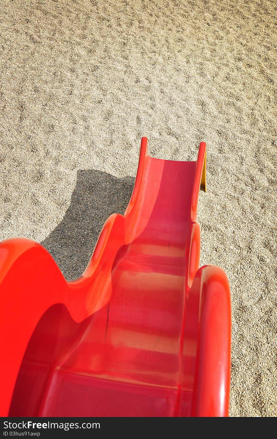 A children play at playground with red slide and sand background on holiday time. A children play at playground with red slide and sand background on holiday time.