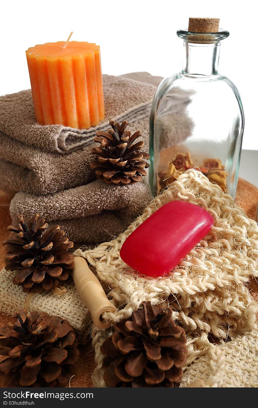 Soap, bottle, candle, towels and pine cones placed on a towels, on a white background. Soap, bottle, candle, towels and pine cones placed on a towels, on a white background