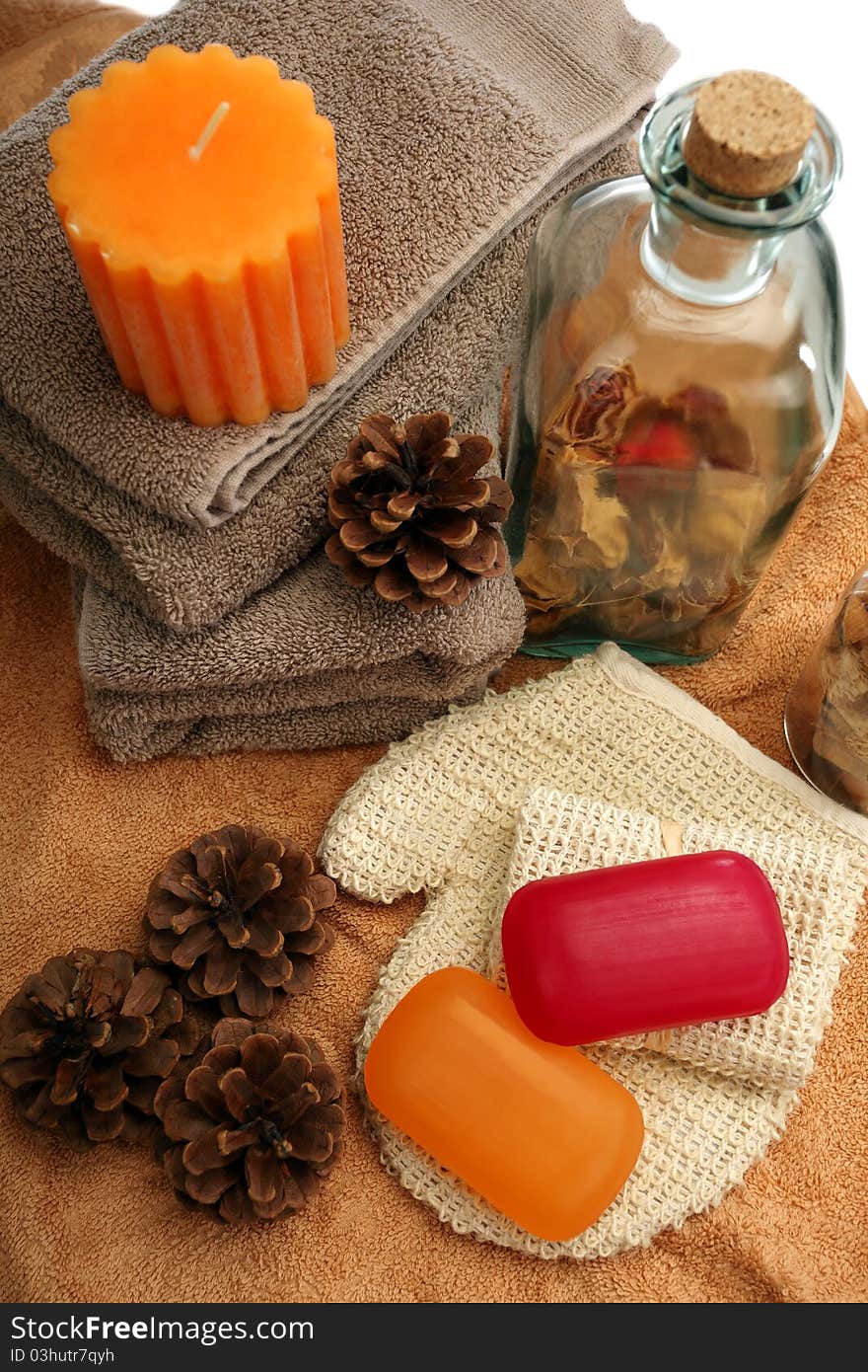 Soaps, bottle, candle, towels and pine cones placed on a towels, on a white background. Soaps, bottle, candle, towels and pine cones placed on a towels, on a white background