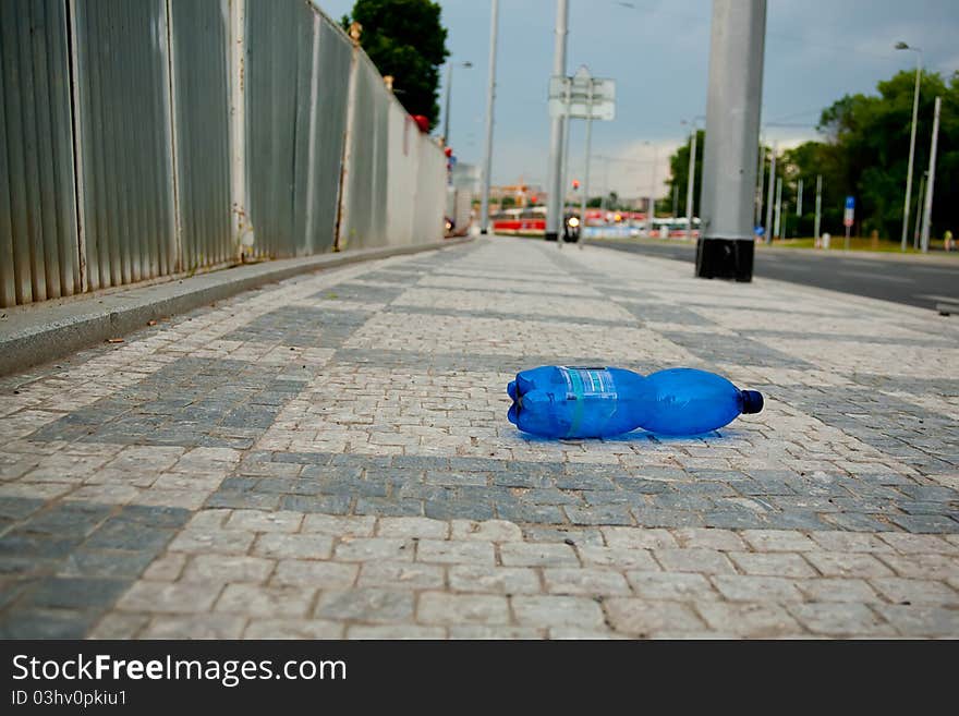 Wasted PET bottle on sidewalk. Soft focus image, focus on the bottle.