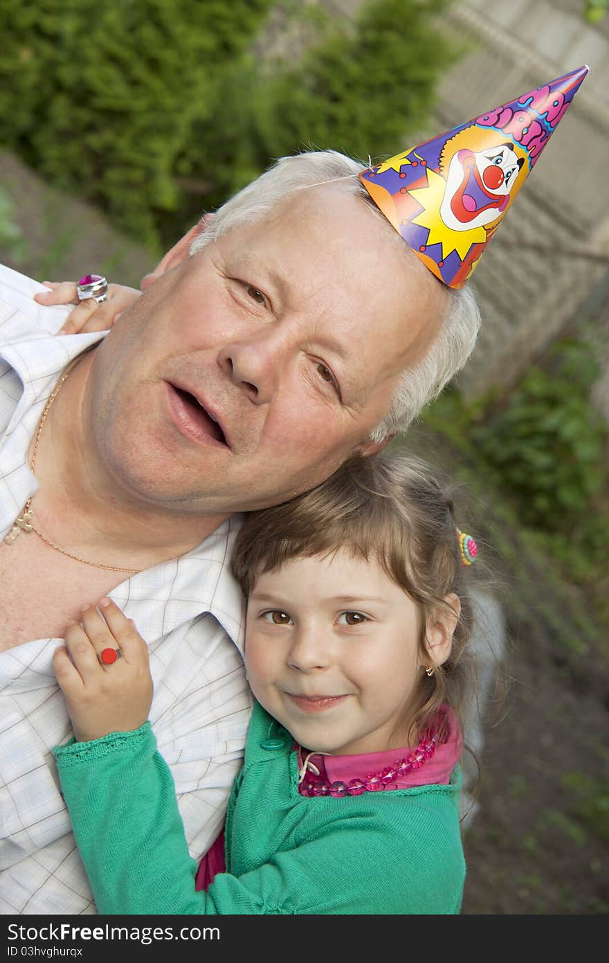 The child embraces the grandfather in a cap. The child embraces the grandfather in a cap