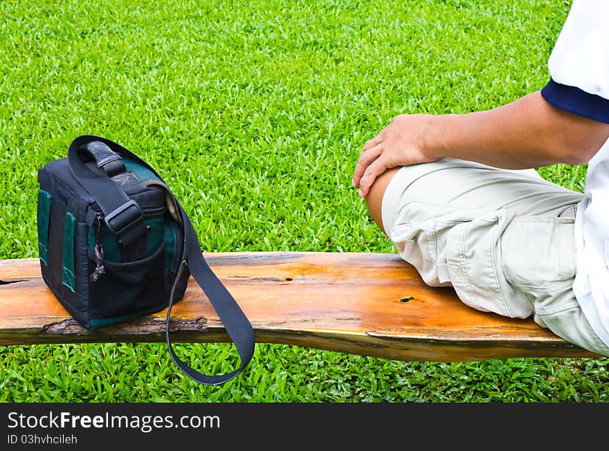 Sit with handbag on a wooden bridge over the piece of grass. Sit with handbag on a wooden bridge over the piece of grass.