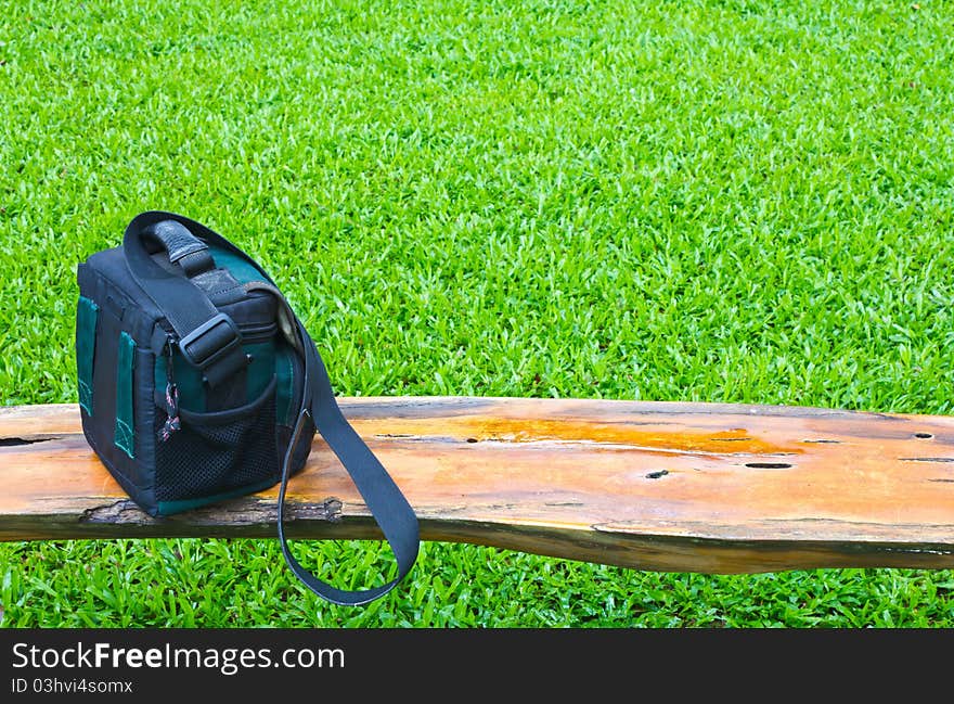 Sit with handbag on a wooden bridge over the piece of grass. Sit with handbag on a wooden bridge over the piece of grass.