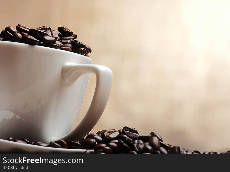 Cup of coffee with beans on yellow background