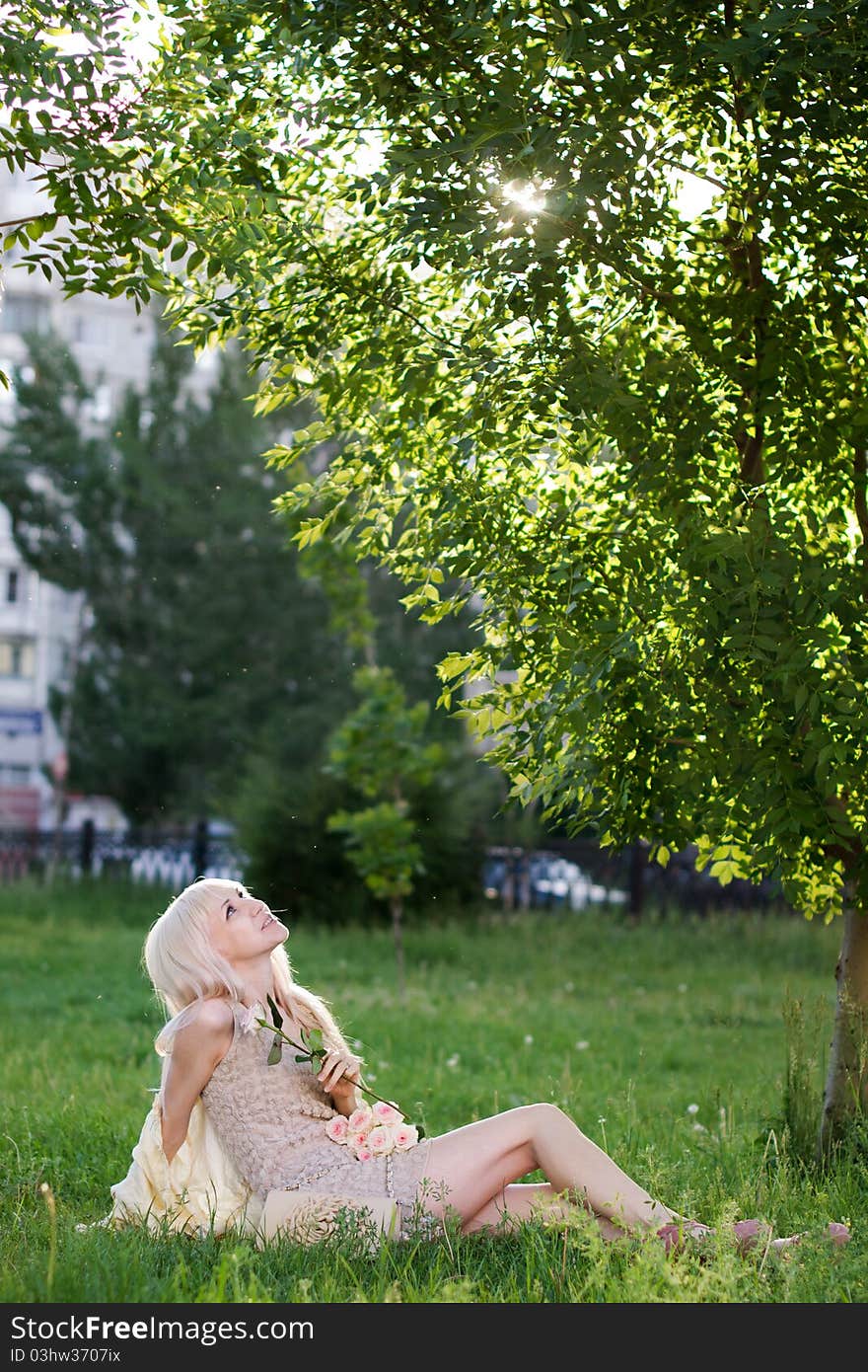 Beautiful girl sitting on the grass in the park on sunny day