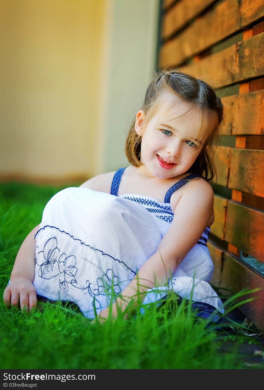 A sweet 4 year old is looking happily at the camera. She is leaning against a red timber wall. She looks relaxed and happy. A sweet 4 year old is looking happily at the camera. She is leaning against a red timber wall. She looks relaxed and happy.