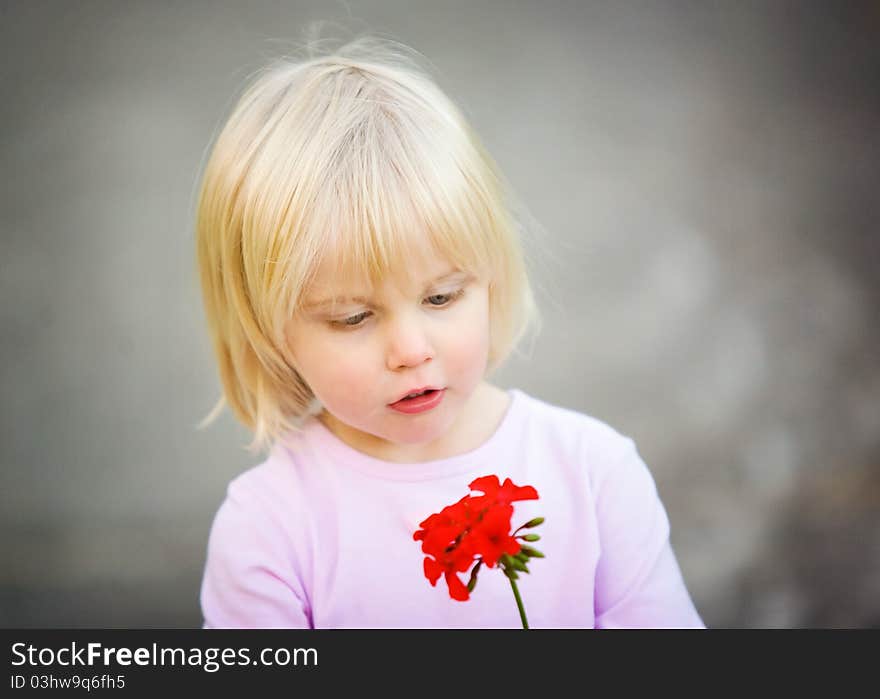 Cute little girl looking at her red flower