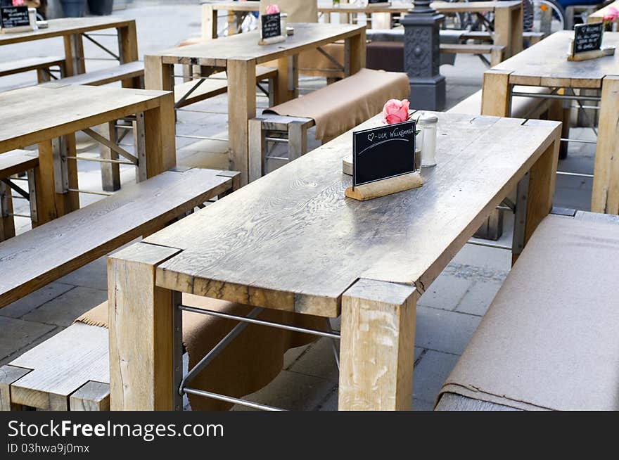 Table decoration outside in a street at a rustically restaurant with heavy, wooden tables and benches. Table decoration outside in a street at a rustically restaurant with heavy, wooden tables and benches