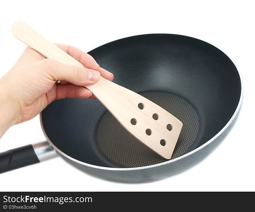 Frying pan with wooden spatula, isolated with human hand towards white background