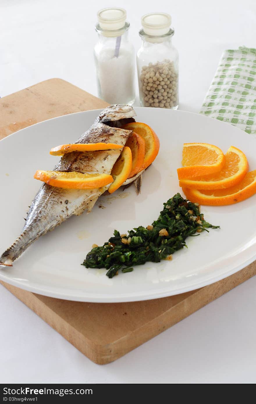 A plate of Torpedo Scad/mackerel scad fish served with sliced oranges, parsley and salsa verde. A plate of Torpedo Scad/mackerel scad fish served with sliced oranges, parsley and salsa verde