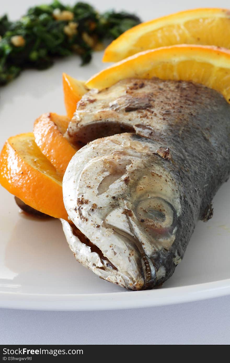 Close-up of a plate of Torpedo Scad/mackerel scad fish served with sliced oranges, parsley and salsa verde. Close-up of a plate of Torpedo Scad/mackerel scad fish served with sliced oranges, parsley and salsa verde