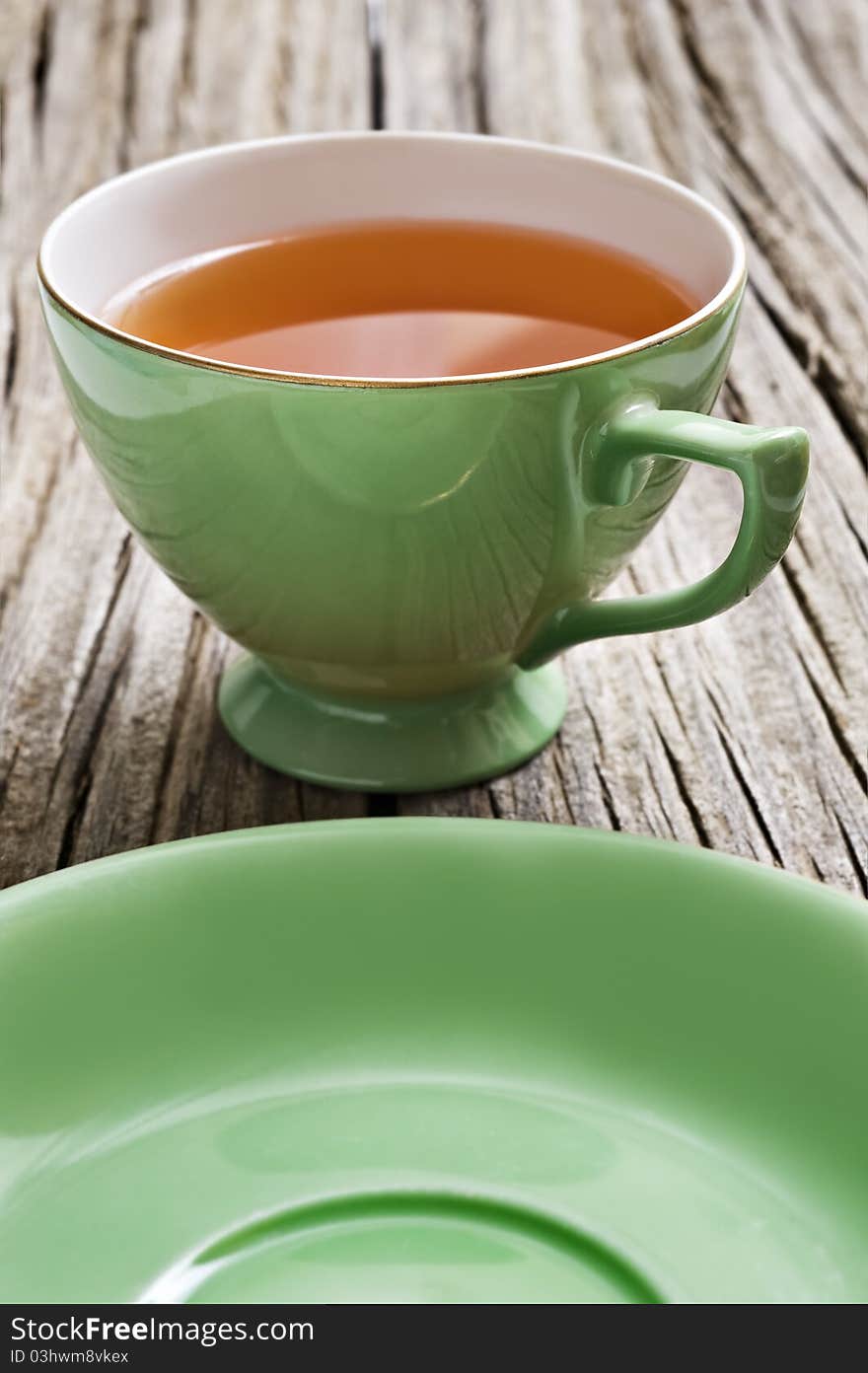 One antiques cup with tea on a rustic background