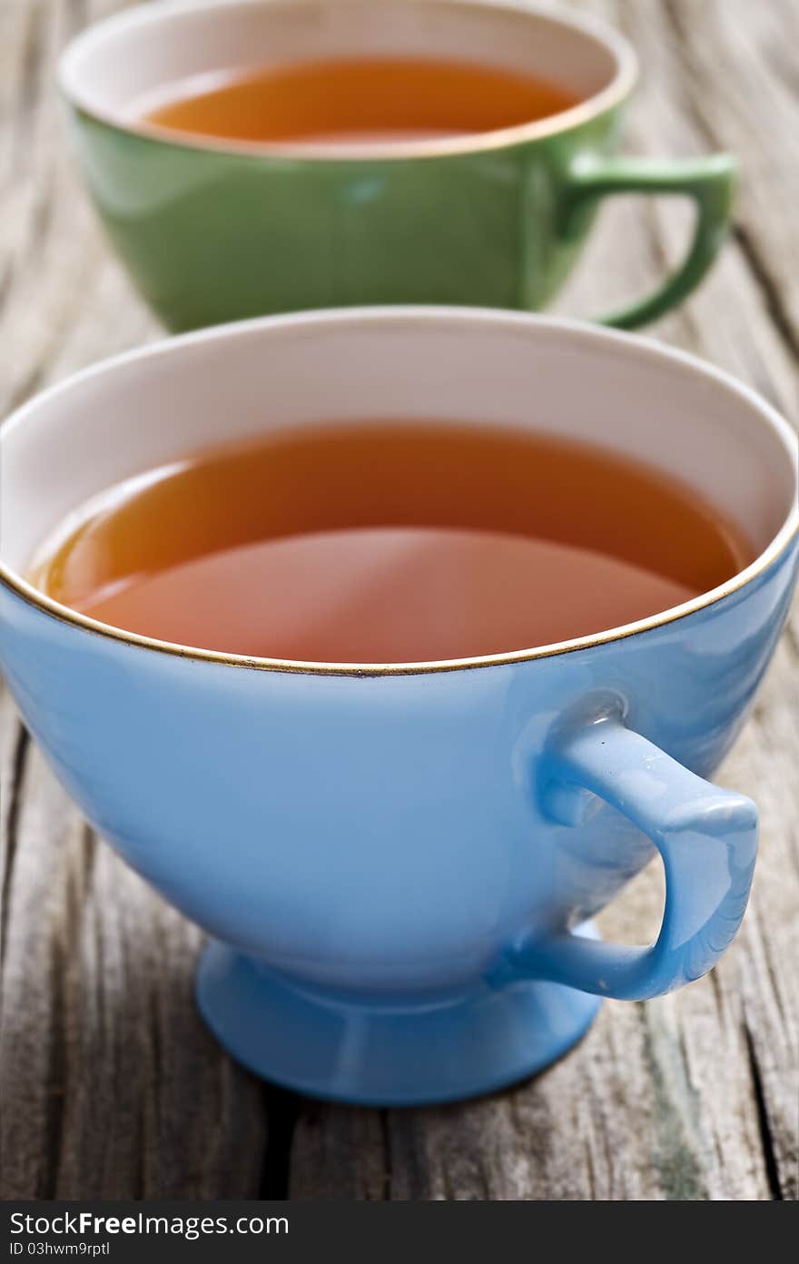 Two antiques cups with tea on a rustic background