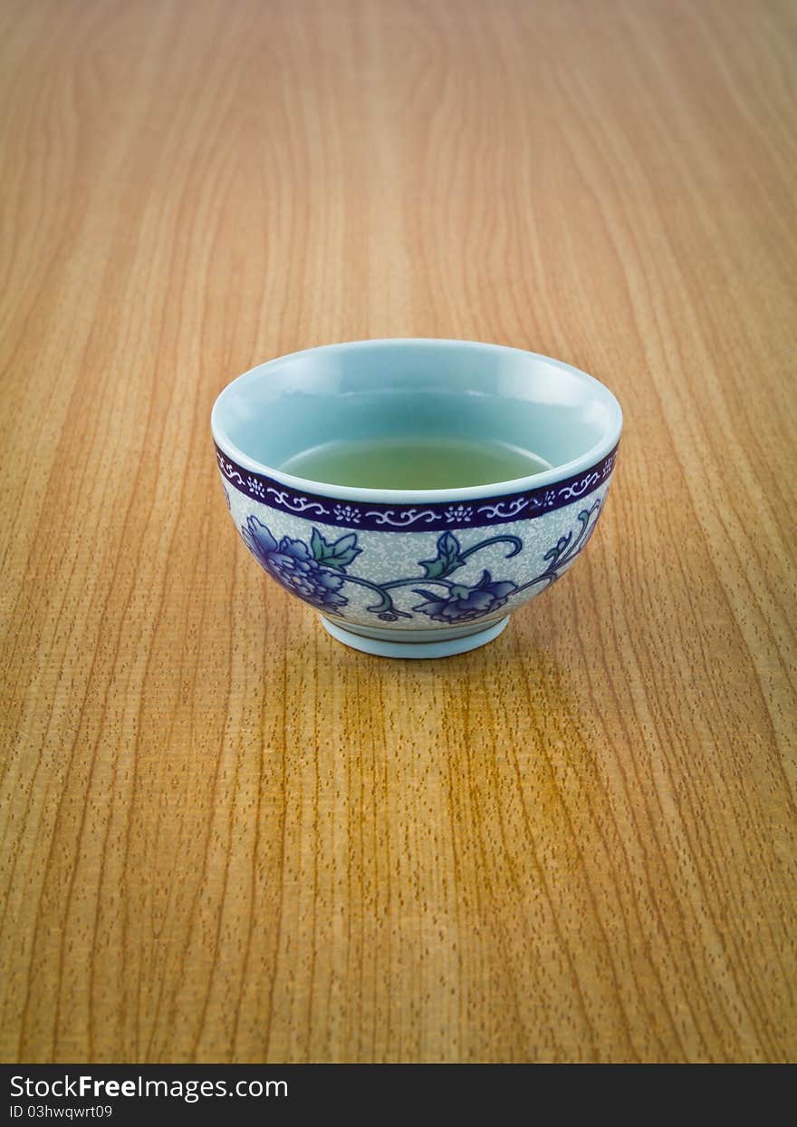 Small cup of tea in Chinese's style on wooden table. Small cup of tea in Chinese's style on wooden table