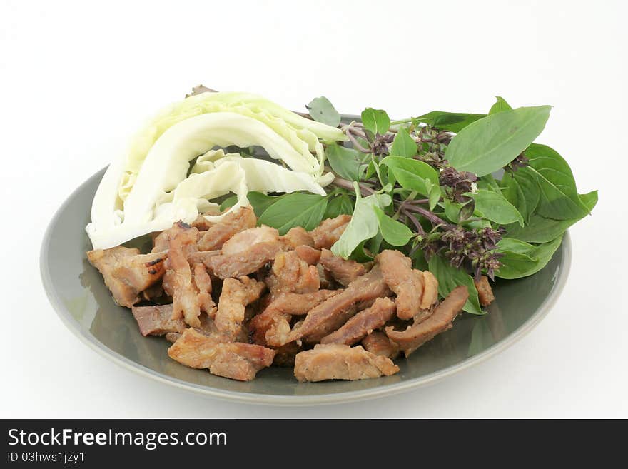 Thai style grilled pork on disk with cabbage and sweet basil