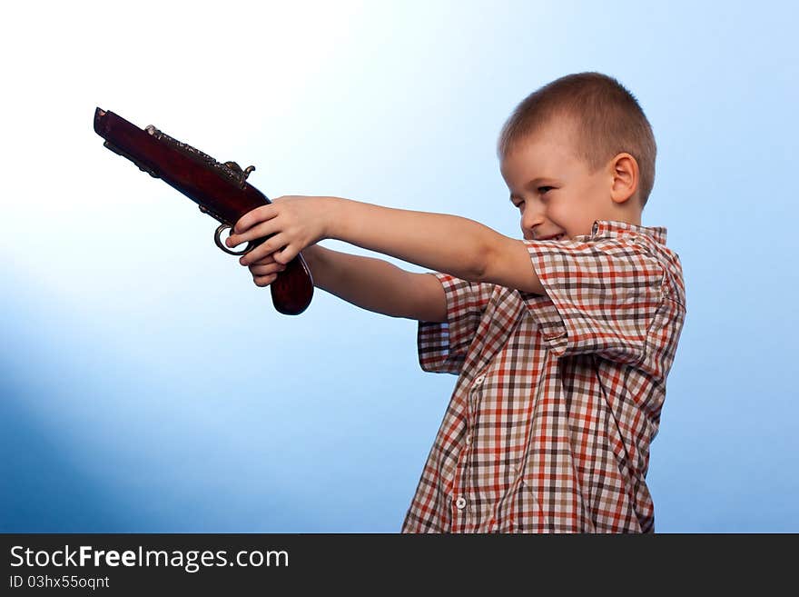 Cute boy playing with the gun against blue background