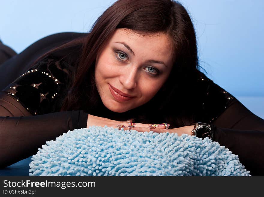 Beautiful woman lying on pillows on blue background