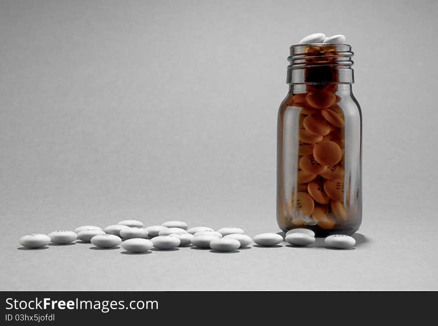 Bottle of white pills/tablets on plain backround with space for text