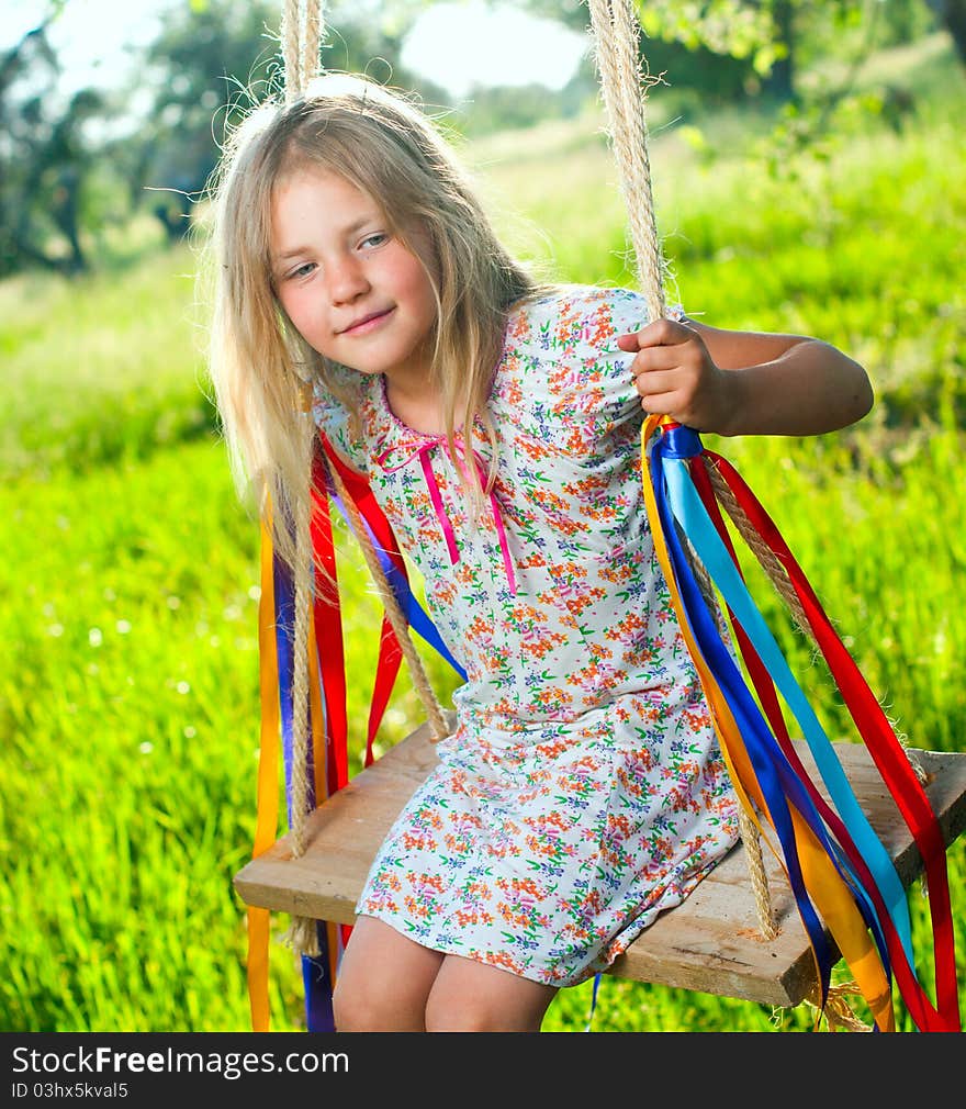 Young cute girl on swing with ribbons in the garden. Young cute girl on swing with ribbons in the garden