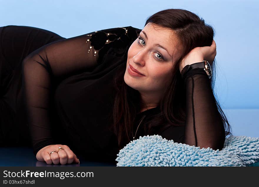 Beautiful woman lying on pillows on blue background