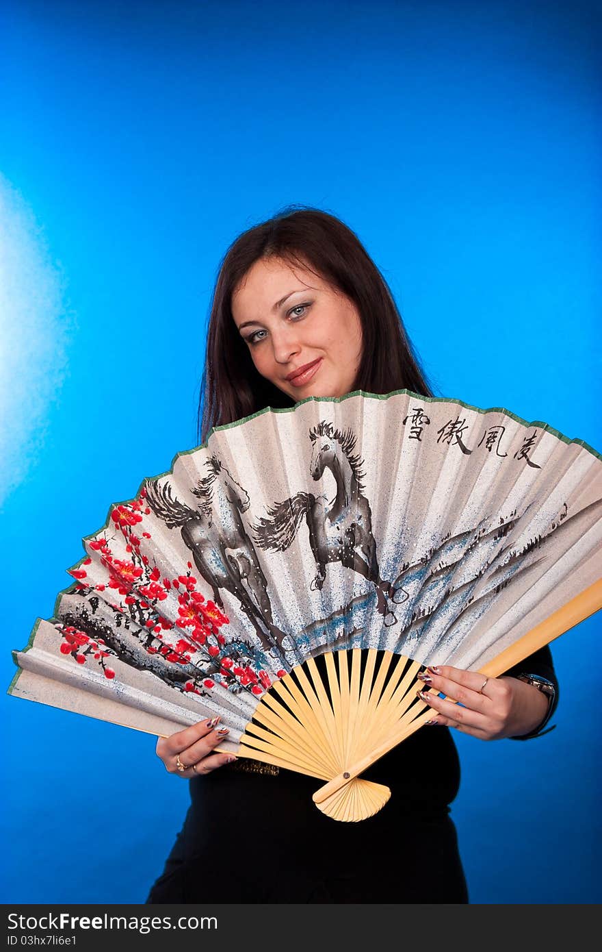 Portrait of a beautiful woman with fantail on blue background