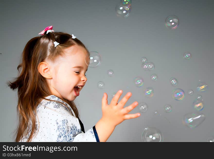 Cute little girl playing with bubbles in the studio. Cute little girl playing with bubbles in the studio