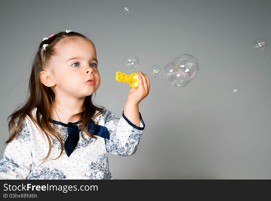 Cute little girl playing with bubbles in the studio. Cute little girl playing with bubbles in the studio