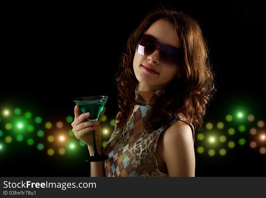 Young woman with a green cocktail on a black background
