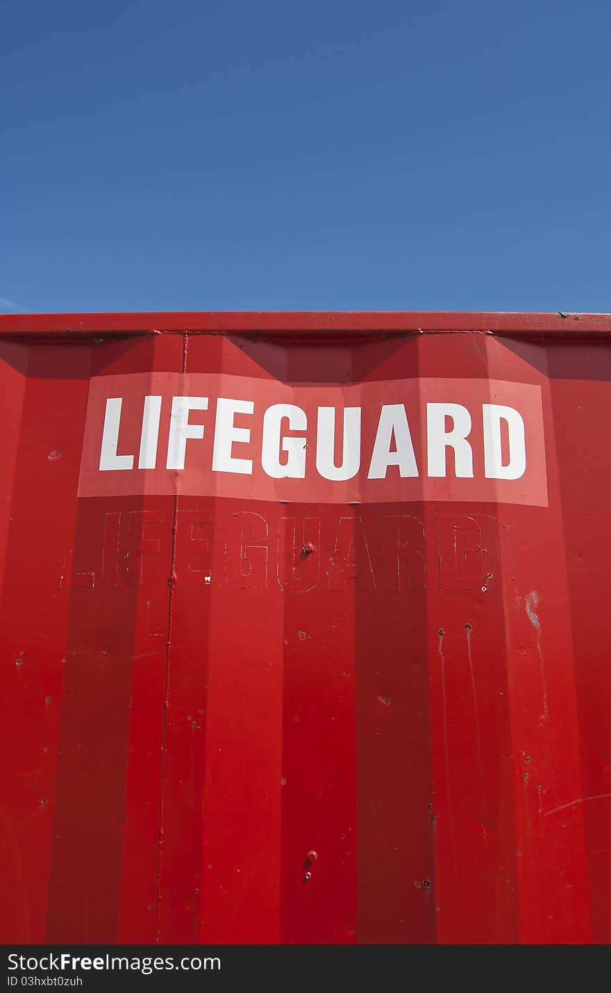 Lifeguard sign on red house with blue sky