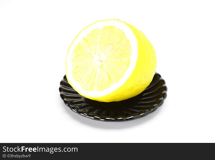 Lemon on black plate on a white background. Lemon on black plate on a white background