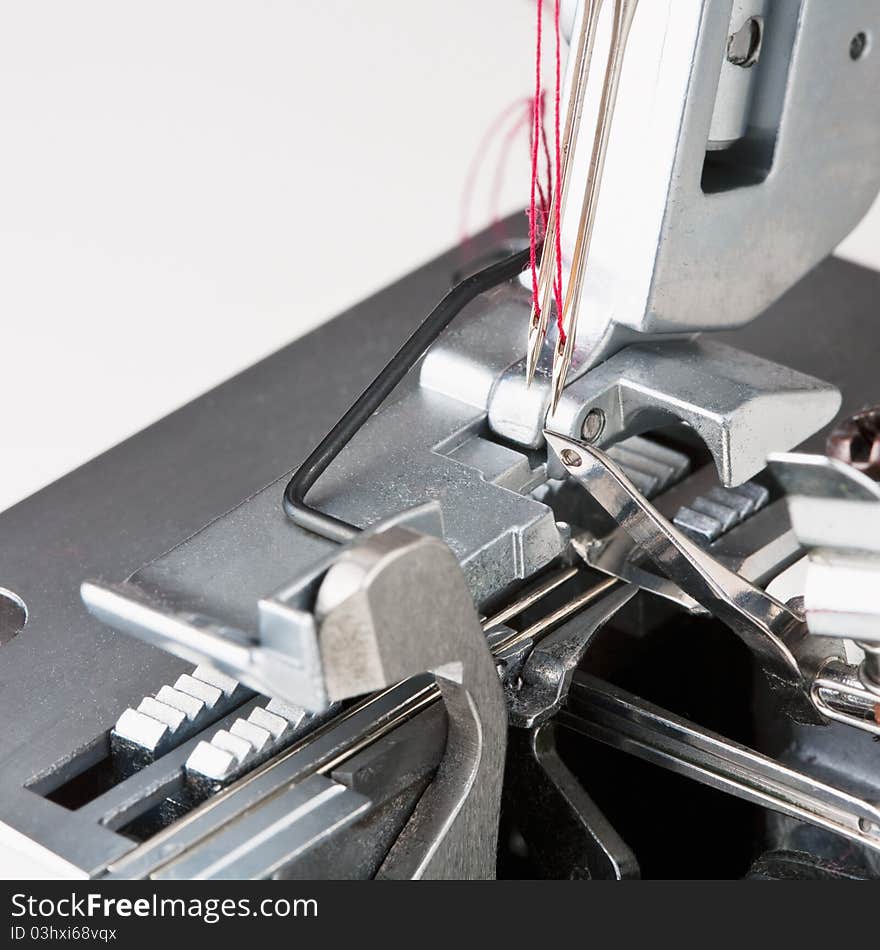 Needles with thread in overstitching machine closeup