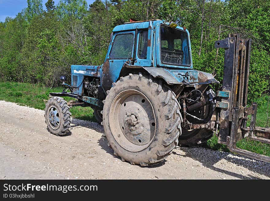 Old vintage tractor on country road in forest, spring sunny day. Old vintage tractor on country road in forest, spring sunny day