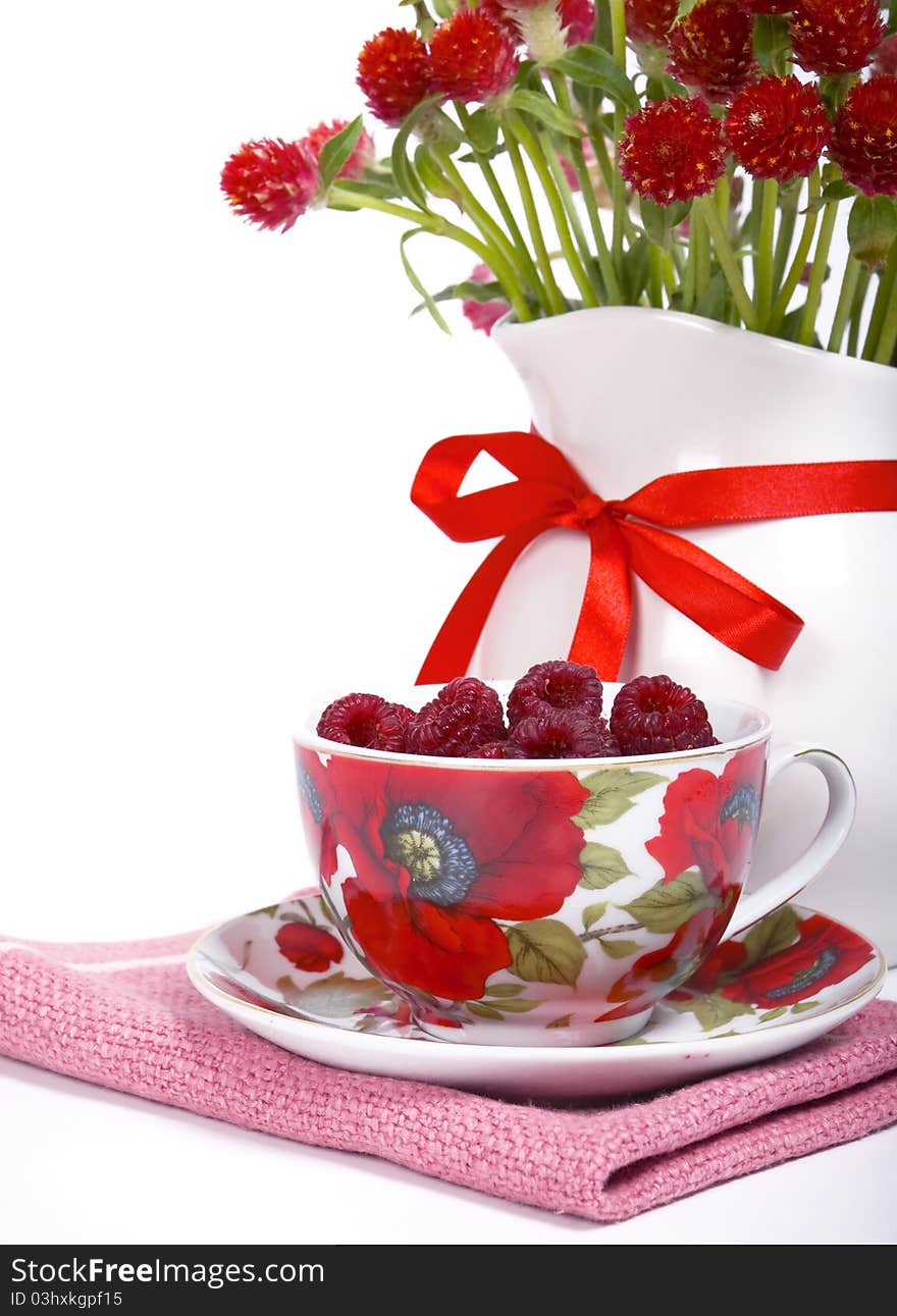 Raspberry in a beautiful cup and a bunch of flowers on a white background. Raspberry in a beautiful cup and a bunch of flowers on a white background