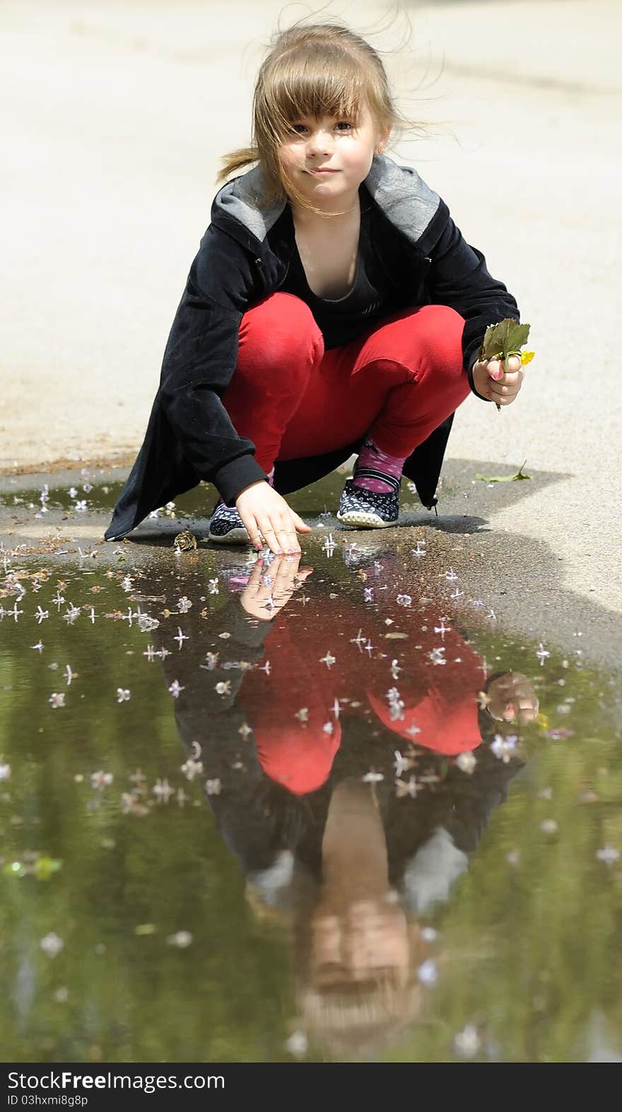 Young girl playing with puddle in spring season. Young girl playing with puddle in spring season