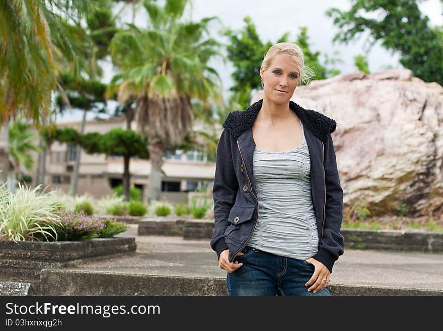 Young attractive woman stands in the park with palm trees