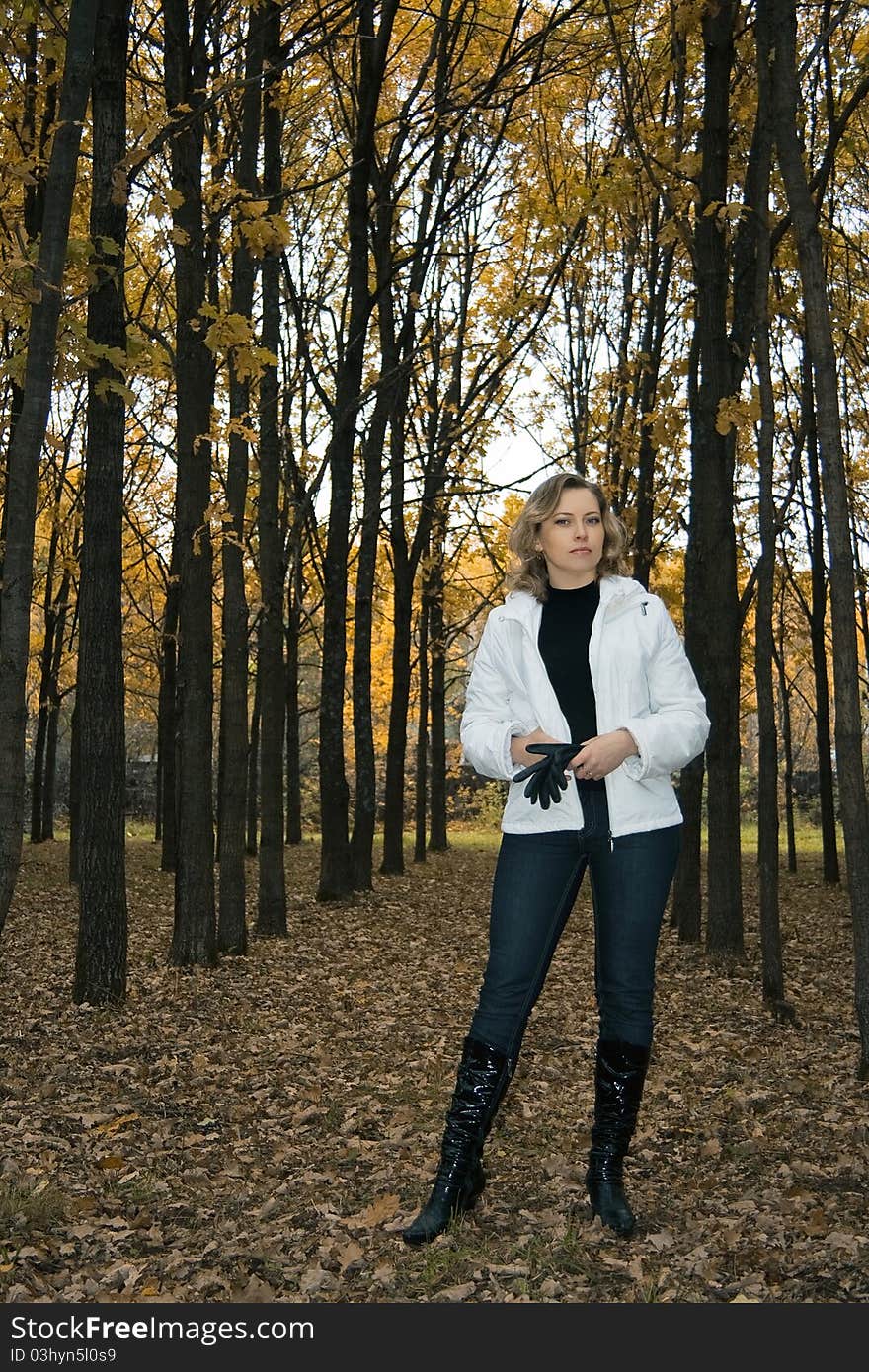 Pretty woman in white jacket standing in gloomy autumn park. Pretty woman in white jacket standing in gloomy autumn park