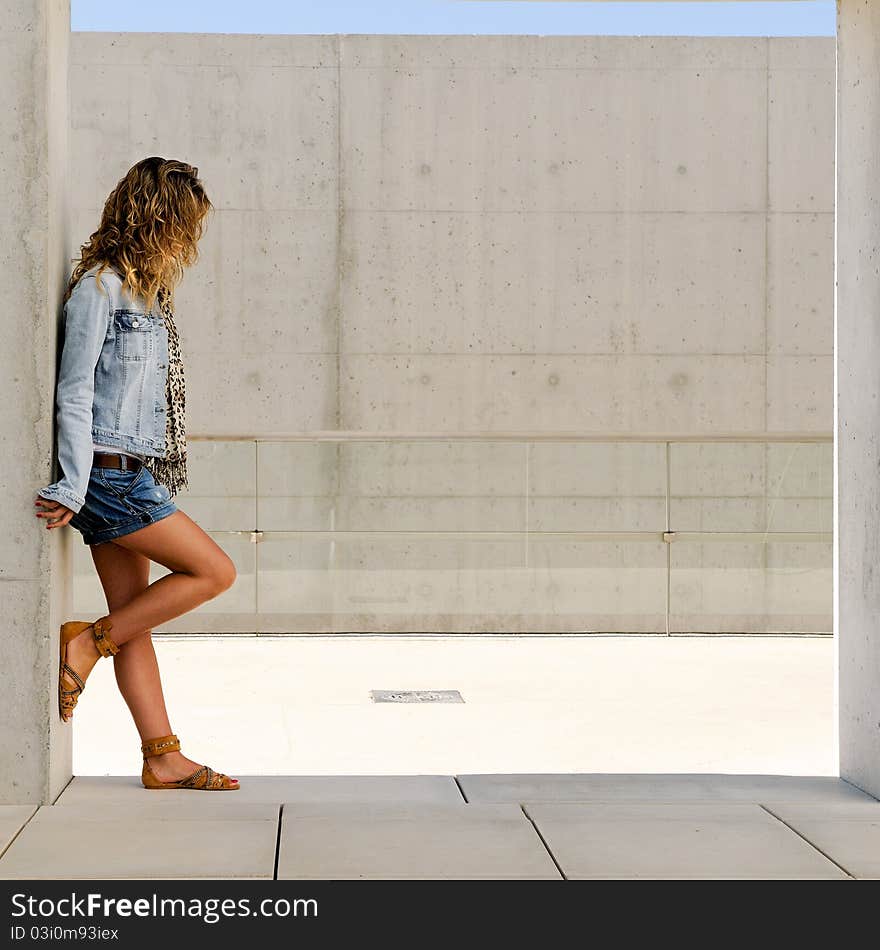 A pretty blonde girl resting on the wall