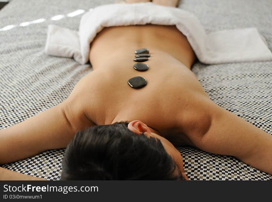 Woman getting hot stone massage with black pebbles