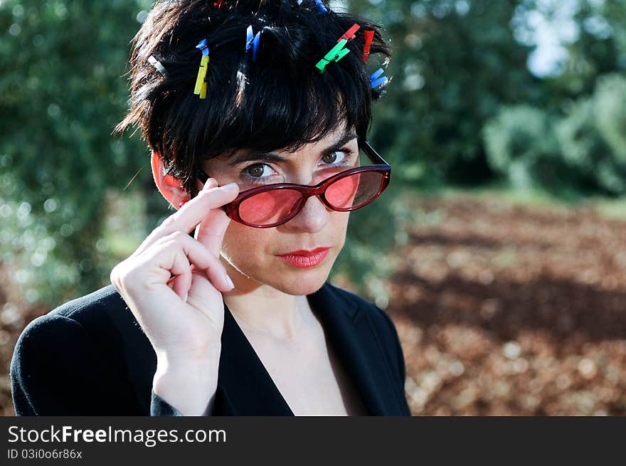 Funny picture of a girl with her hair adorned with clothespins, wearing cheerful sunglasses subject with her hands. Funny picture of a girl with her hair adorned with clothespins, wearing cheerful sunglasses subject with her hands.