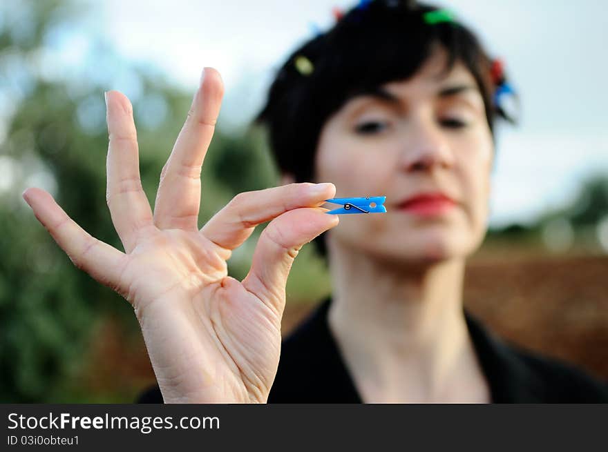 Funny image, using the shallow depth of field to focus attention on the hand of the model, which contains a clothespin. Ironic symbol of consumerism. Funny image, using the shallow depth of field to focus attention on the hand of the model, which contains a clothespin. Ironic symbol of consumerism.