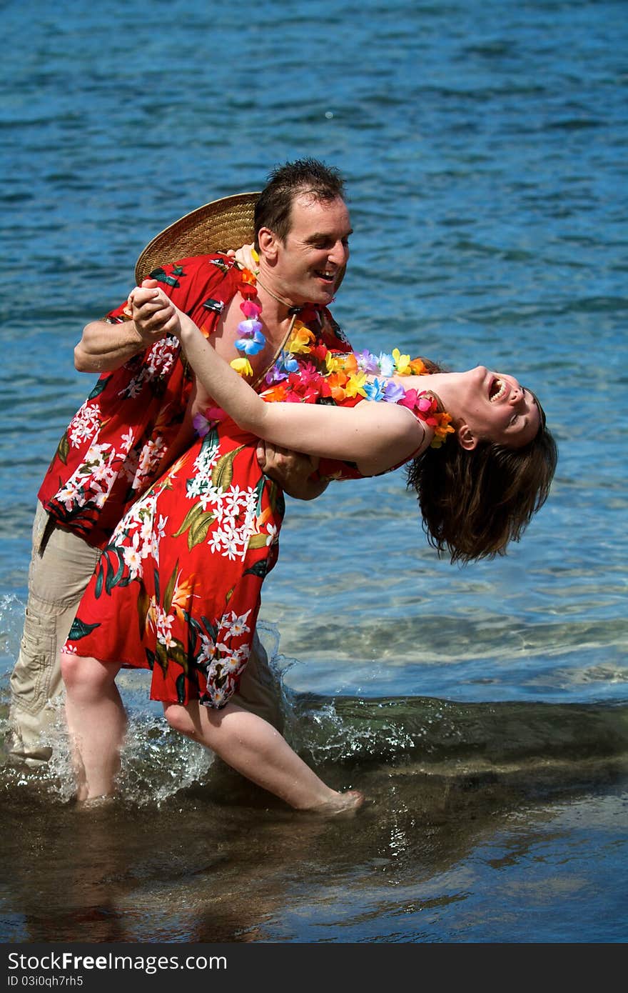 An excited couple on vacation dance in the waves on a beach in Maui, Hawaii. An excited couple on vacation dance in the waves on a beach in Maui, Hawaii.