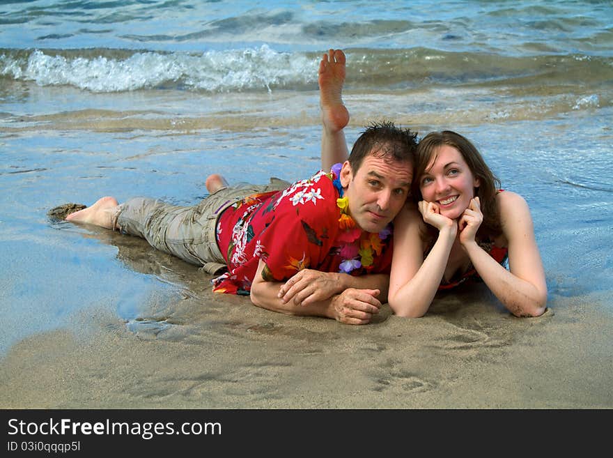 A couple vacationing in Hawaii allows the surf to wash over them as they lie on a beach in Lahaina, Maui. A couple vacationing in Hawaii allows the surf to wash over them as they lie on a beach in Lahaina, Maui.