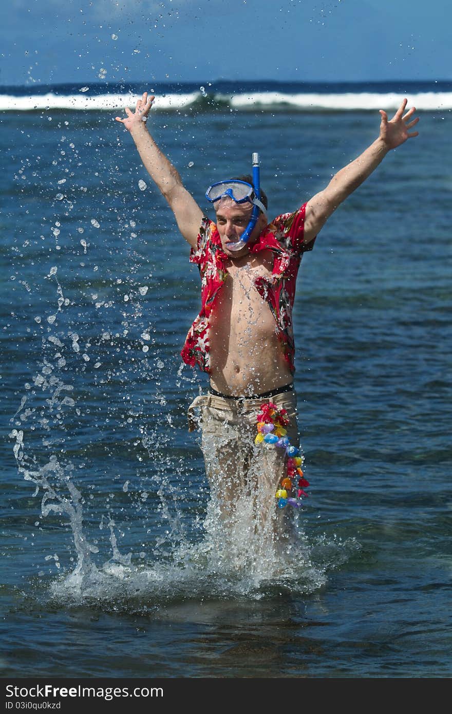 A fully dressed man, wearing a diving mask and snorkel jumps out of the water at a beach in Maui, Hawaii. A fully dressed man, wearing a diving mask and snorkel jumps out of the water at a beach in Maui, Hawaii.